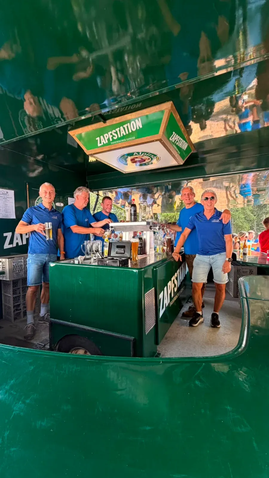 Helfer am Grill unter einem grünen Pavillon.