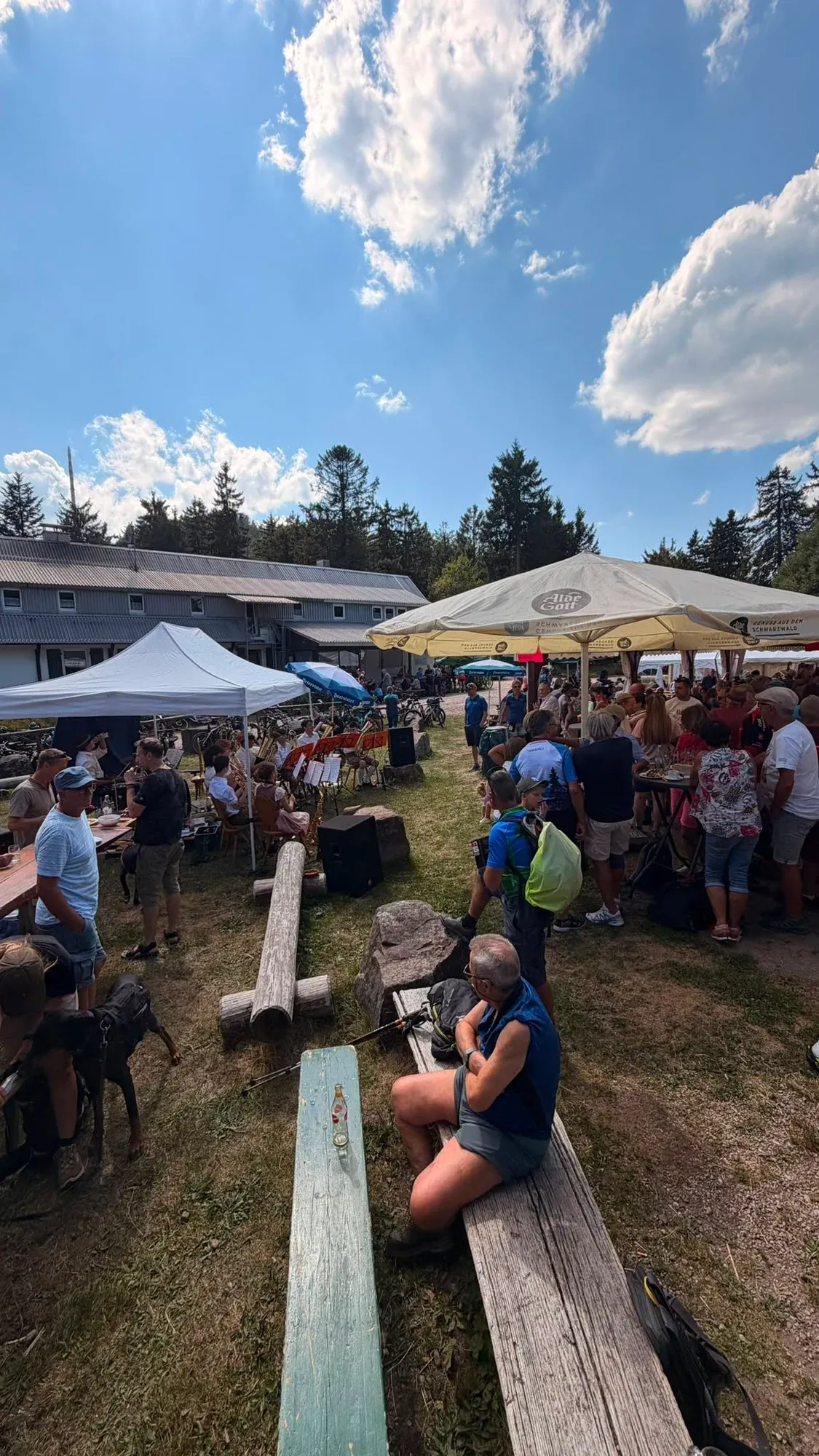 Gäste sitzen im Freien an Tischen vor der Skihütte.