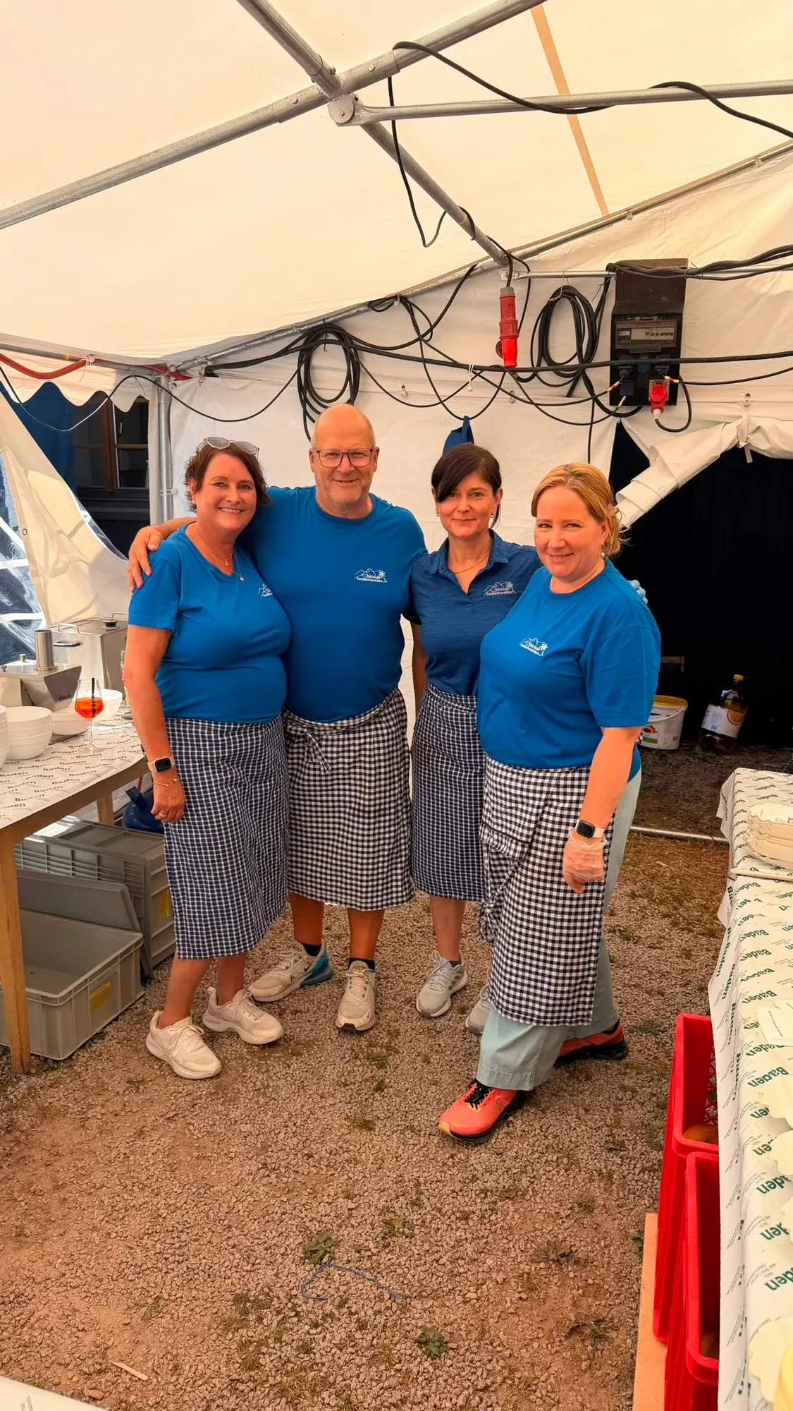 Eine Gruppe in blauen Vereinsoberteilen steht unter einem Festzelt vor der Hütte.