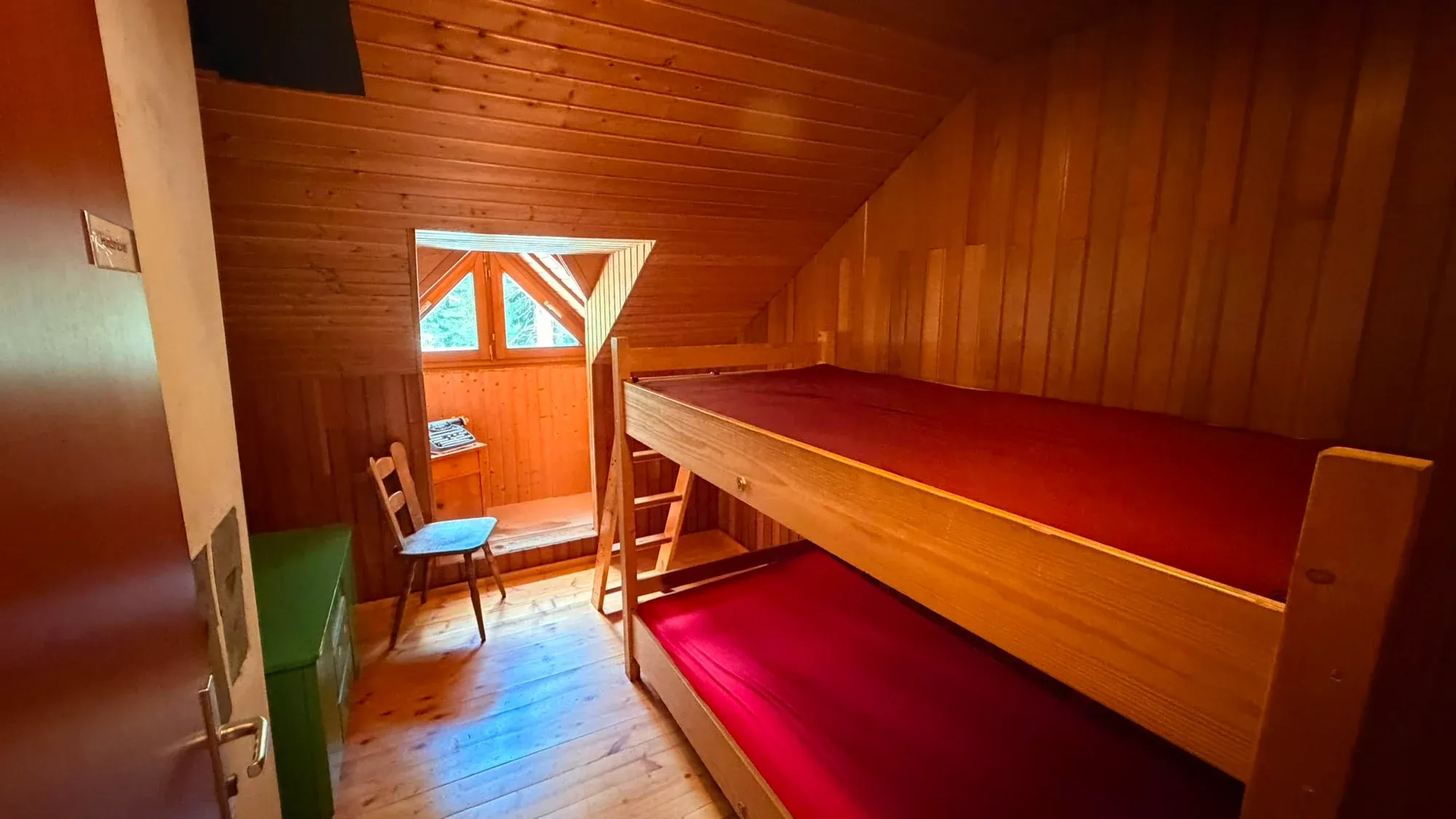 Blick vom Eingang in ein Mehrbettzimmer mit Holzstockbetten.