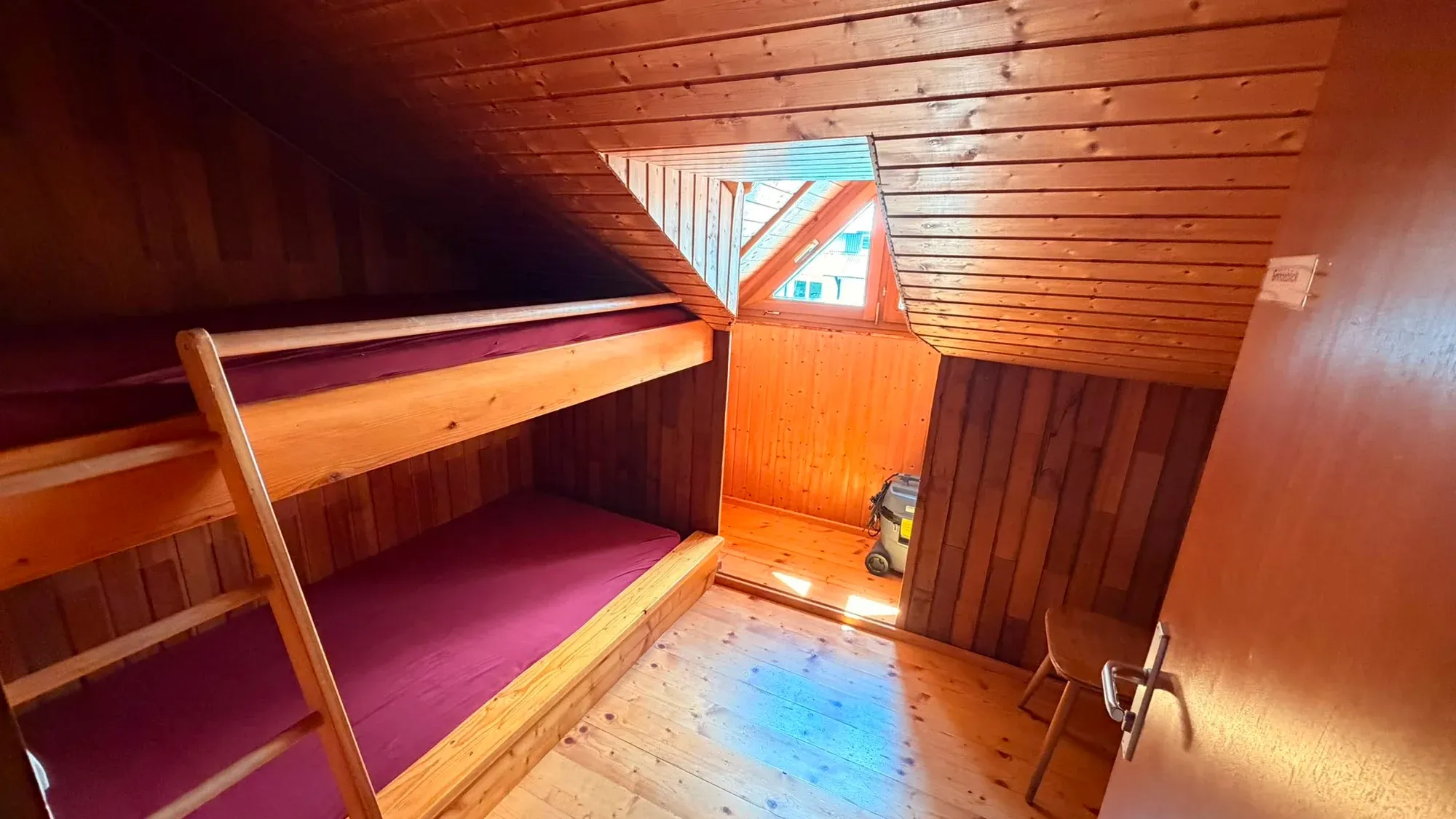 Mehrbettzimmer mit Holzstockbetten und Fenster.