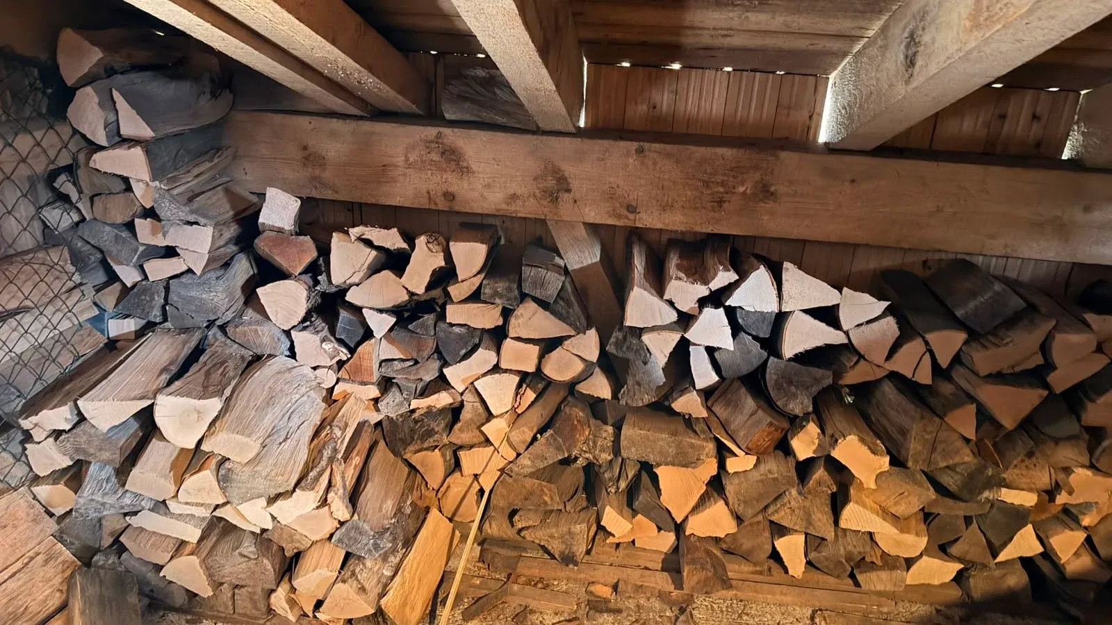 Gestapeltes Brennholz unter dem Dach des Holzschopfs.
