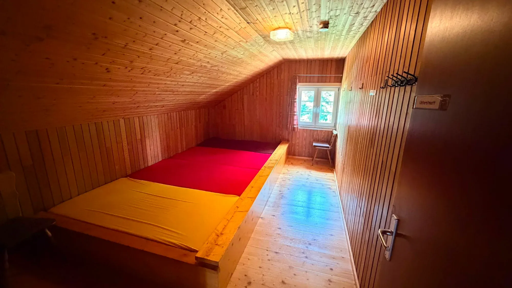 Schlafraum mit zwei nebeneinanderstehenden Betten und Holzverkleidung.