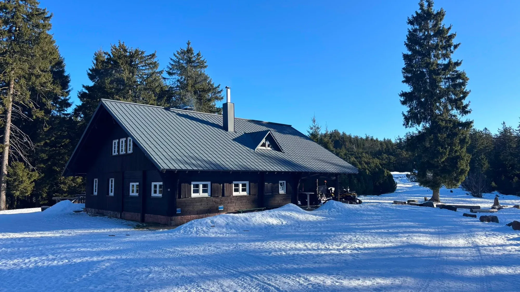 Unsere Skihütte am Ochsenstall zwischen verschneiten Tannen unter blauem Himmel