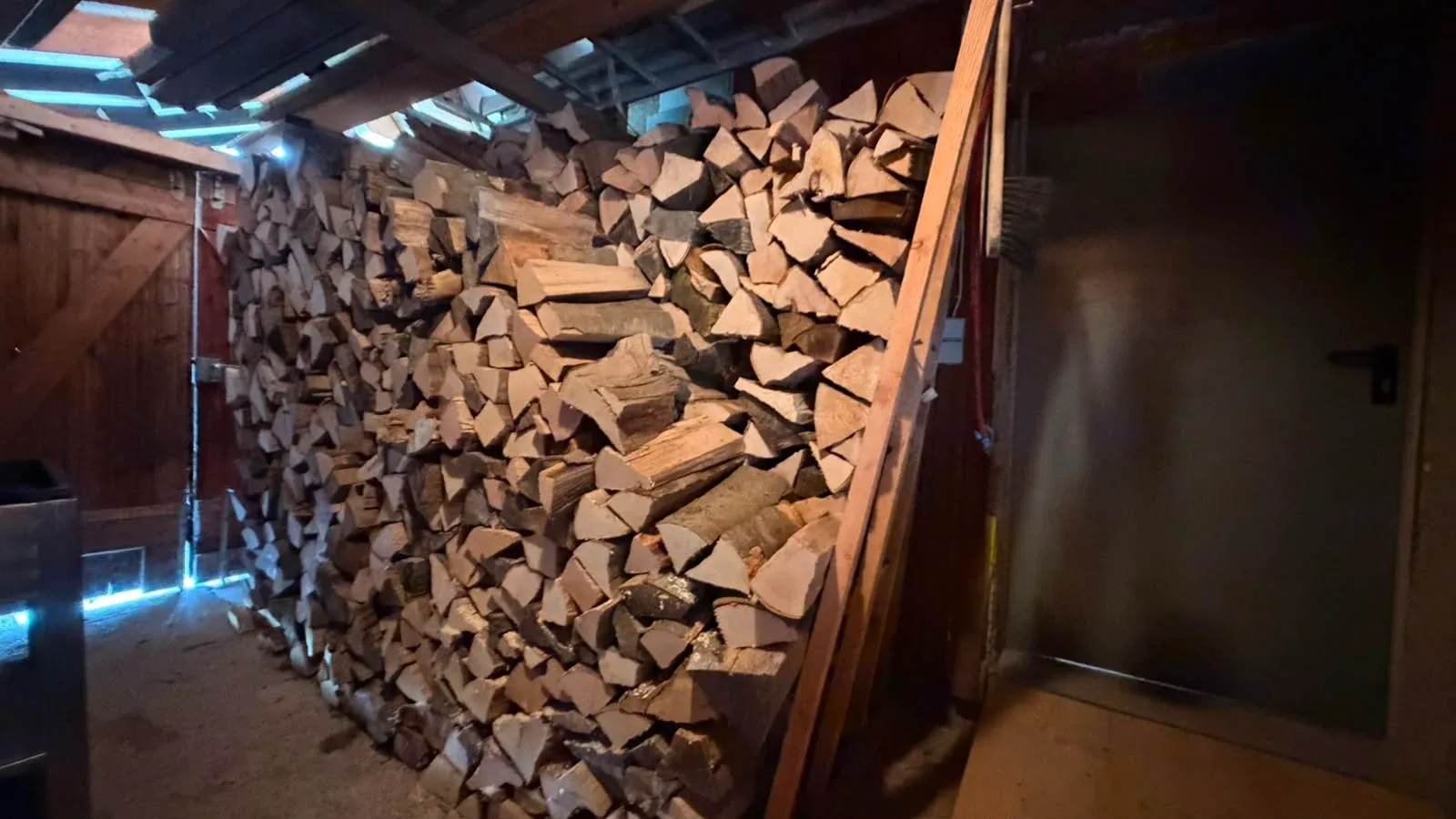 Brennholzstapel im überdachten Lager neben der Hütte.
